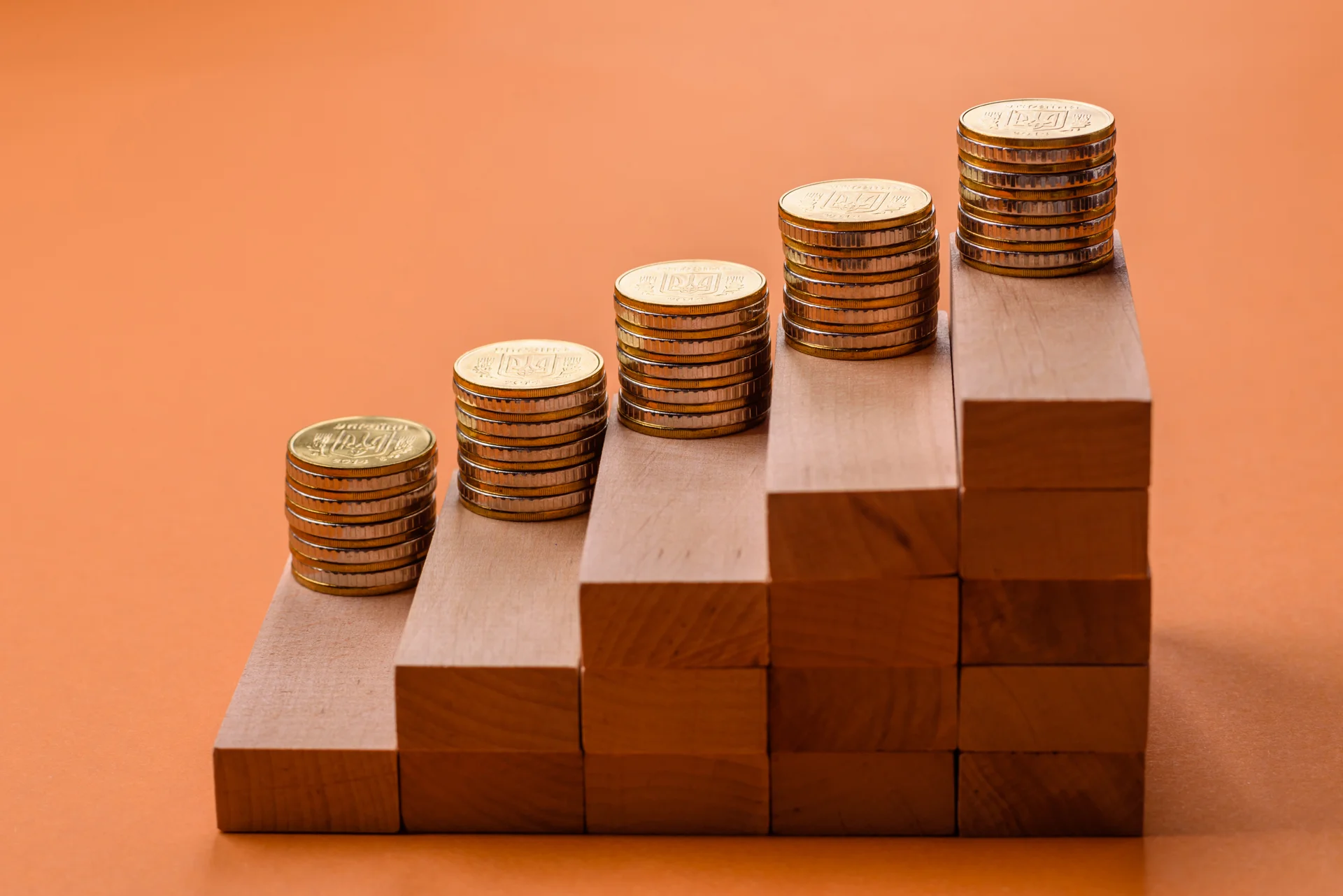 Coins stacked on wooden blocks, representing the intersection of traditional banking and emerging stablecoin technology.