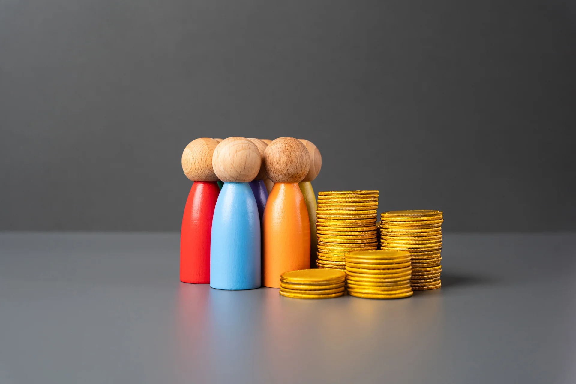 Wooden figures beside stacks of gold coins symbolizing the battle between banks, tech firms, and regulators over stablecoin regulation and control of digital dollar reserves.
